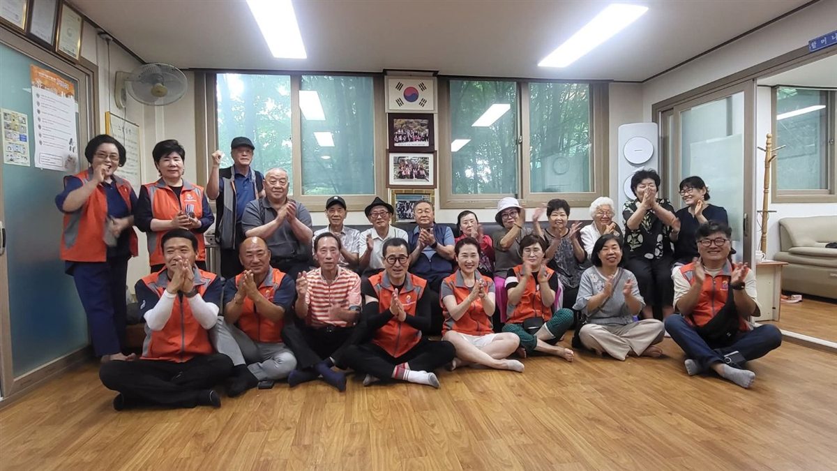 어르신들과 봉사자들이 함께 박수 치는 단체 사진