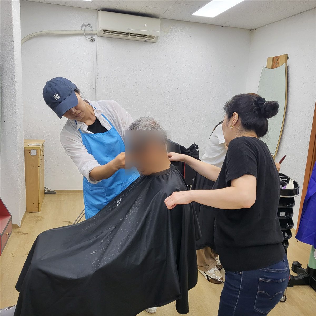 봉사자 두 사람이 머리 손질을 마무리하는 모습