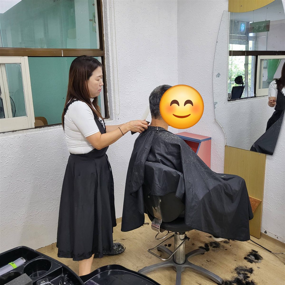 봉사자가 이발기로 머리를 다듬는 모습